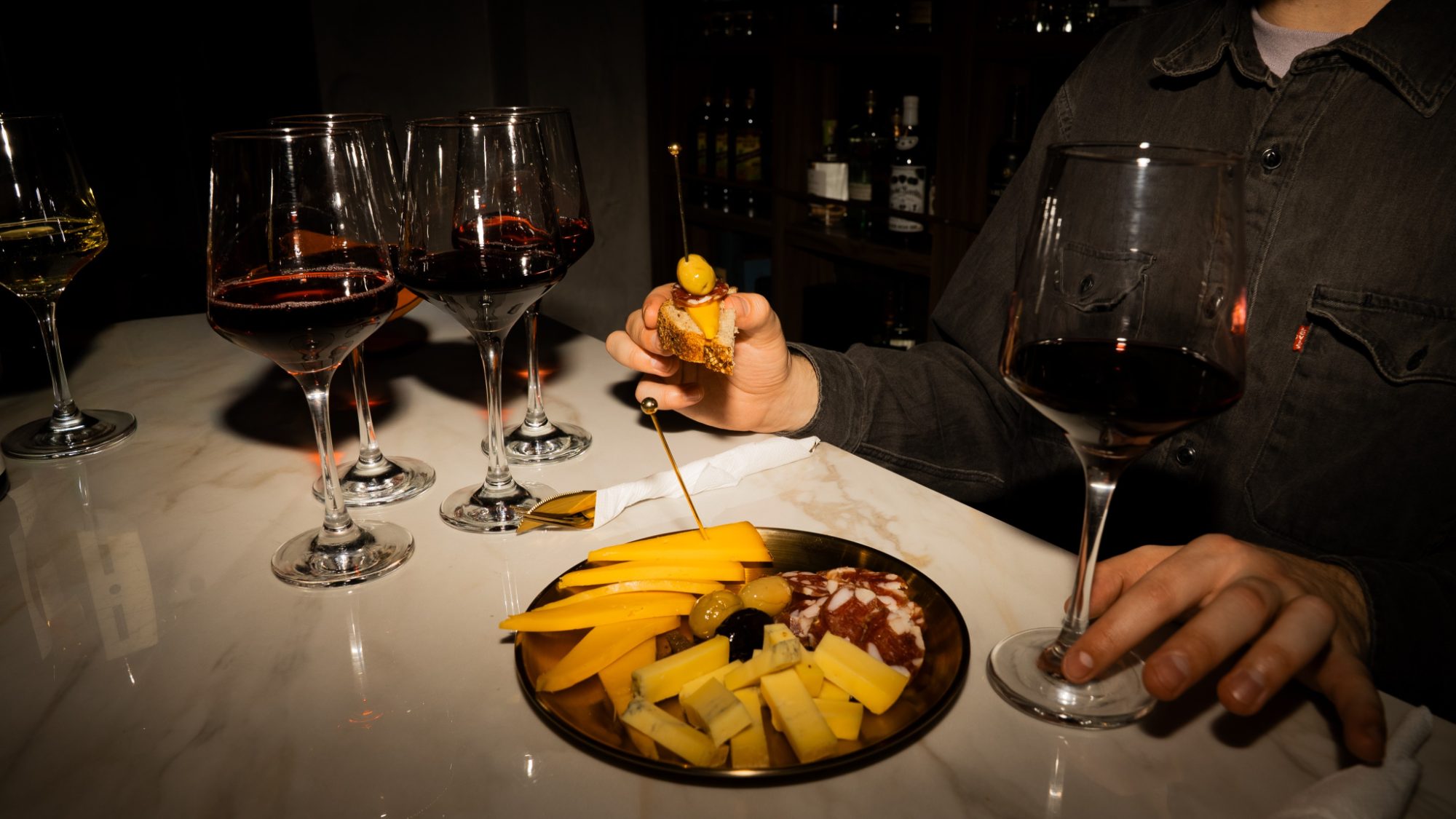 Copas de vino sobre la barra de mármol de Le Morne, junto a una picada de quesos, salame y aceitunas
