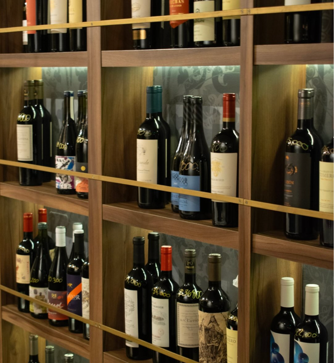 Estantería de madera con botellas de vino iluminadas en la cava de Le Morne