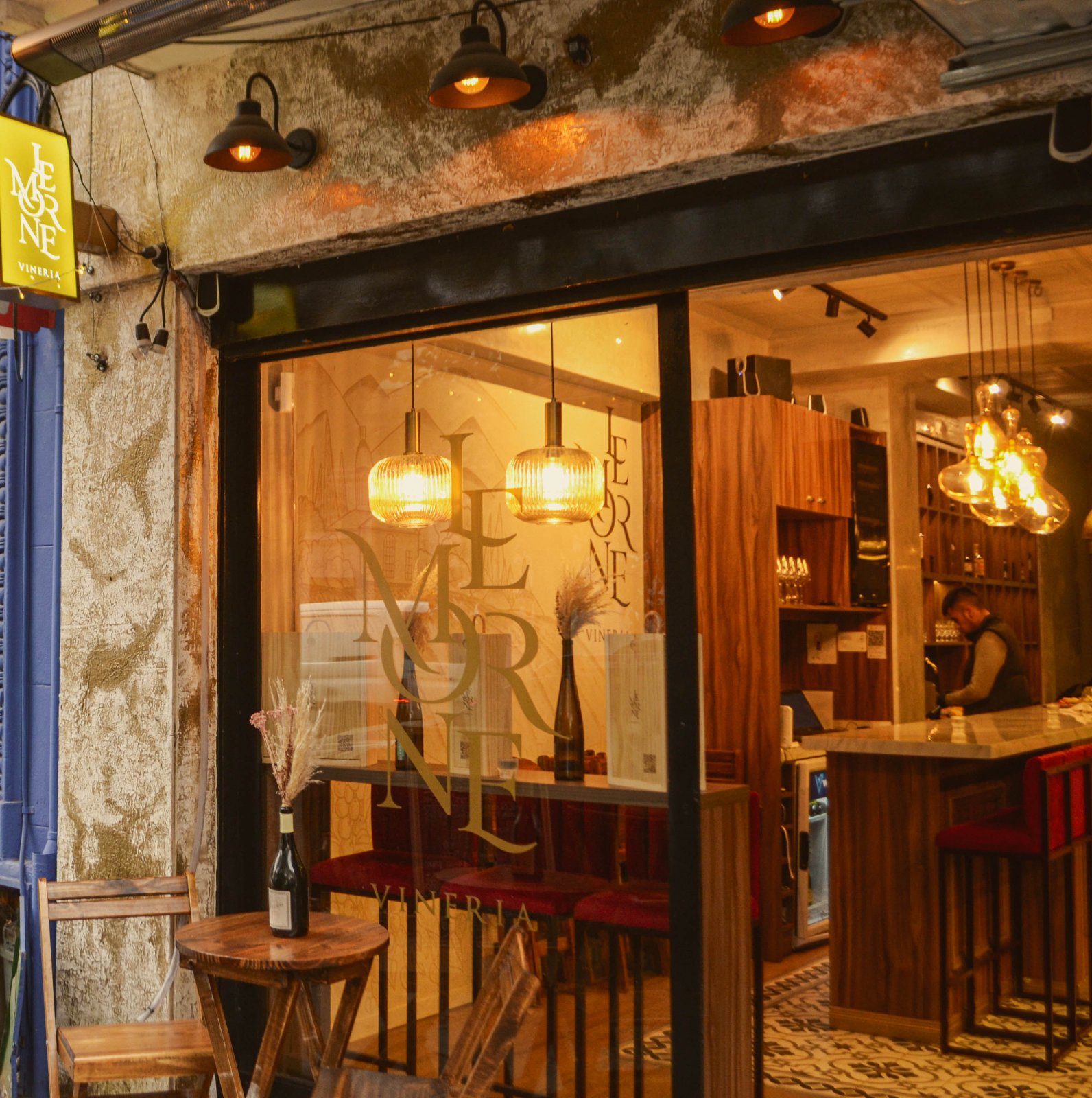 Fachada de Le Morne en Palermo Hollywood: vidriera con el logo, luces cálidas, la barra al fondo y una mesita en la vereda